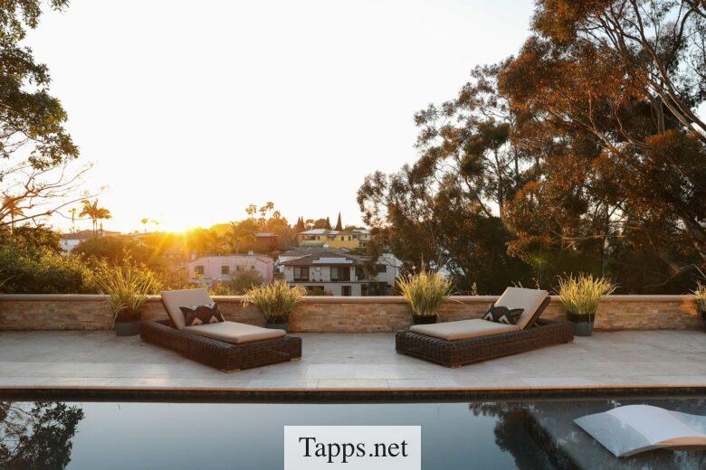 a pool with two lounge chairs and a view of a house
