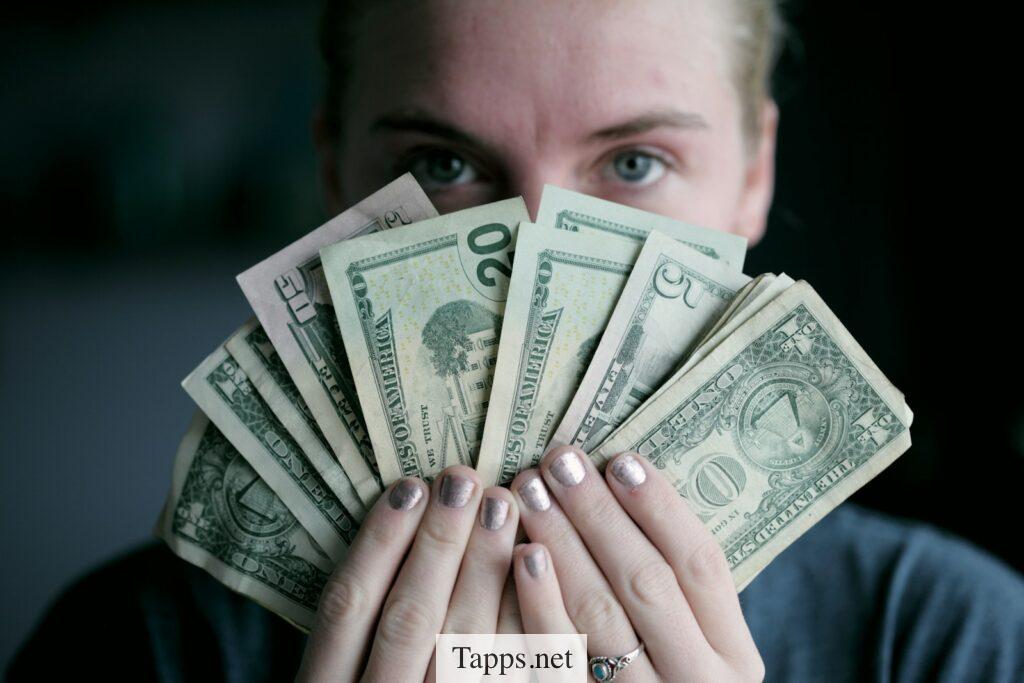 person holding fan of U.S. dollars banknote