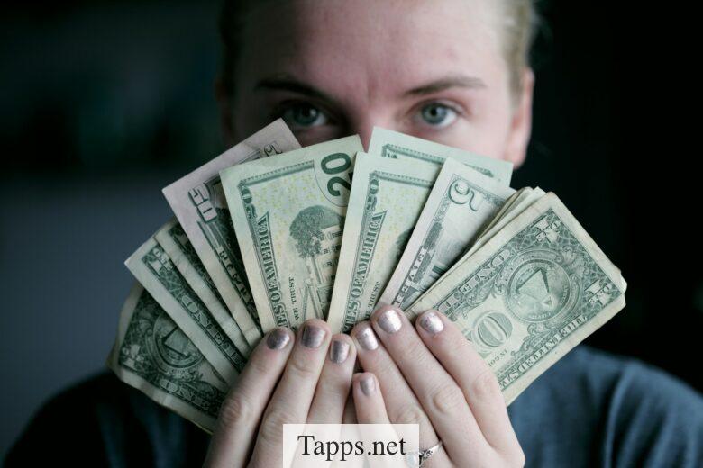 person holding fan of U.S. dollars banknote