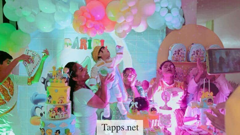 People celebrating baby's birthday with balloons and cakes.